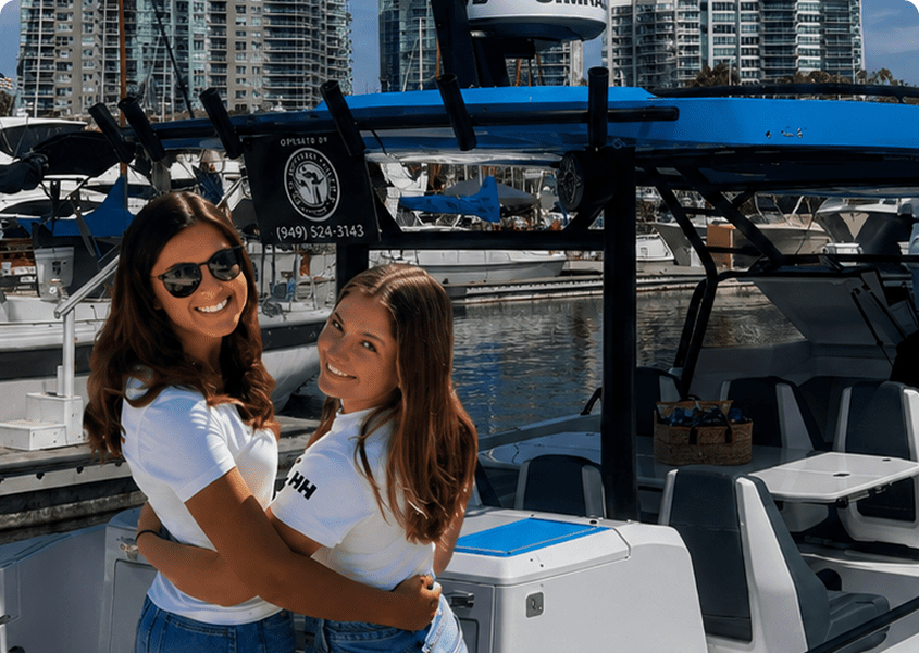 Two women smiling on a boat dock.